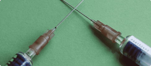 Two needles are shown on a green surface.