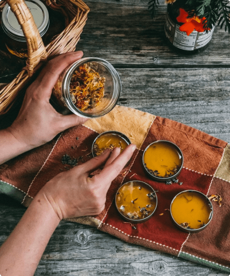 A person holding a bowl of food over some bowls.