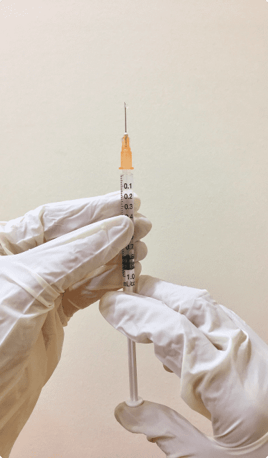 A person in white gloves holding an orange needle.