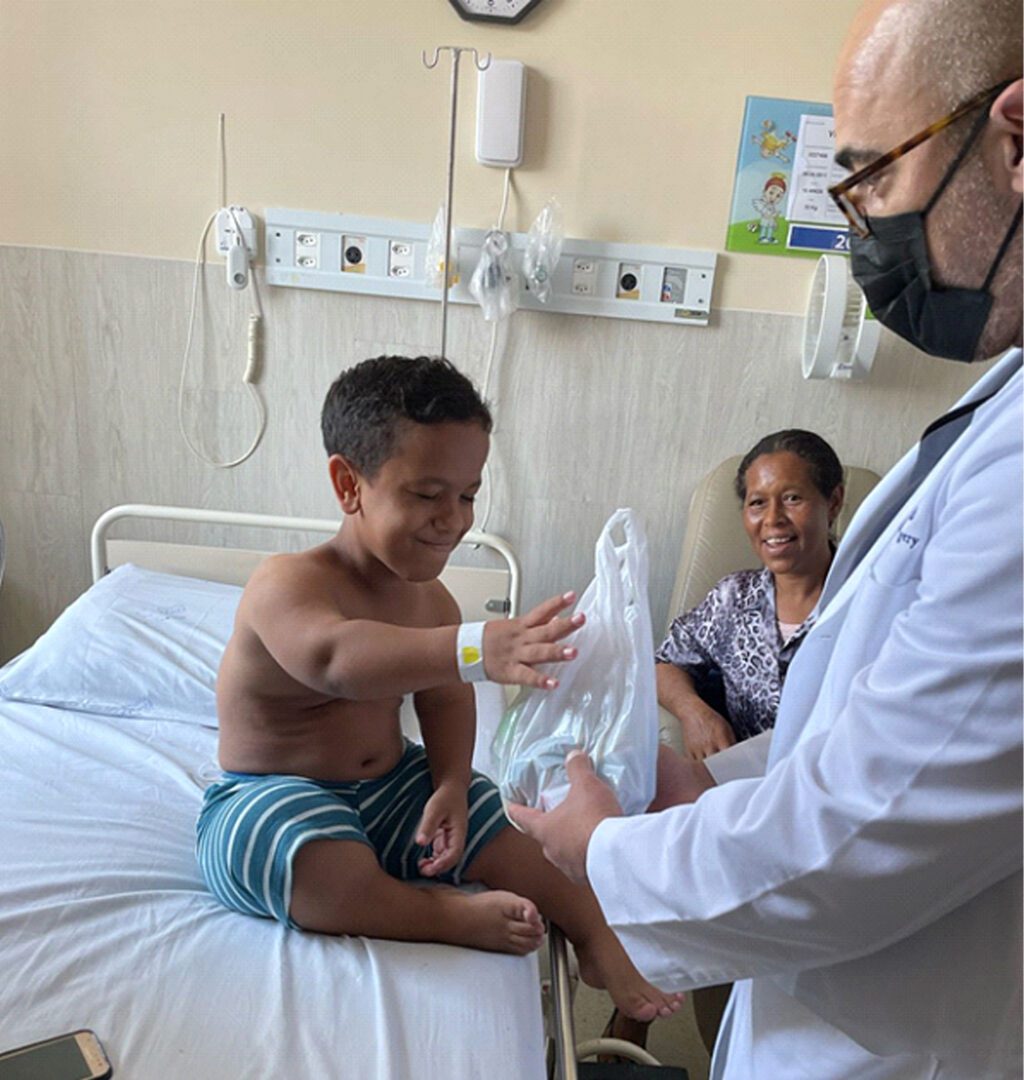 A man in white coat holding a child 's arm.
