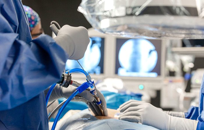 A surgeon is performing surgery on someone 's knee.