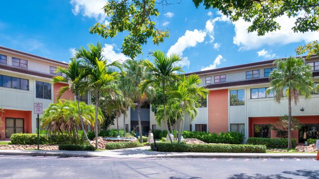 A building with palm trees in the background.
