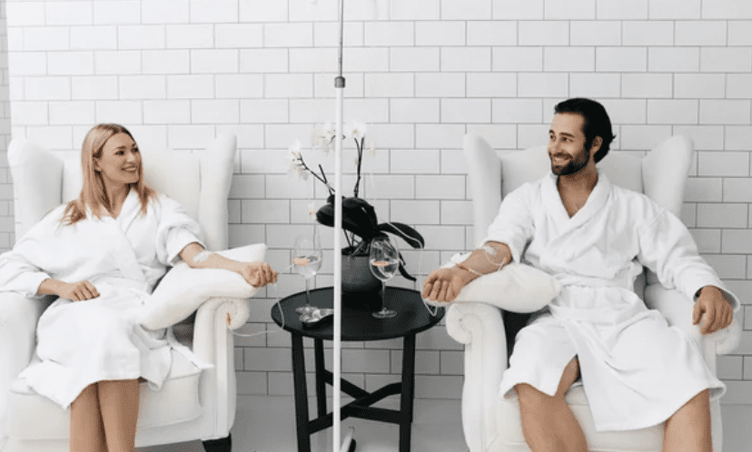 Two people sitting in white chairs with a drink.