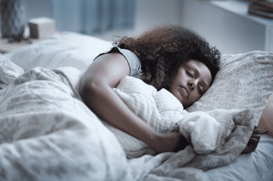 A woman sleeping in bed with her head on the pillow.